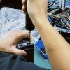 Seorang teknisi sedang melakukan pengujian di meja kerja terhadap panel instrumen digital khusus kendaraan selama proses pemeriksaan garansi